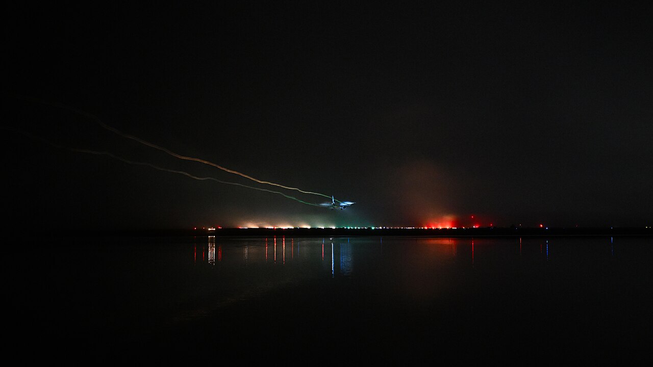 夜雾里飞机进近，地面跑道灯列在黑暗中排开：入口绿灯、中线白灯、末端红灯